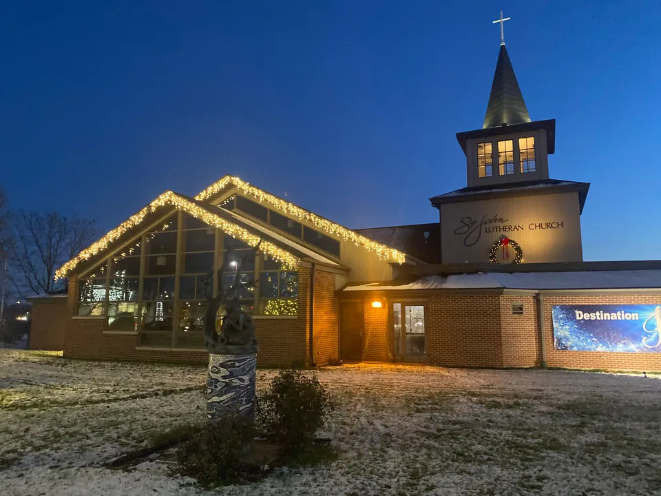 Christmas roofline lights and a wreath on a church at dusk