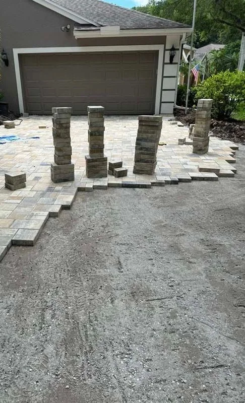 Partially laid driveway pavers with stacked blocks and exposed base
