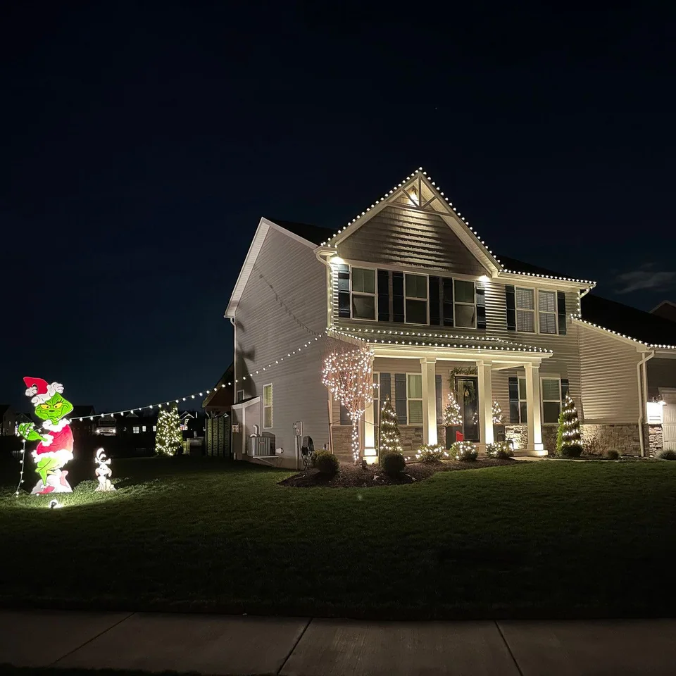 White roofline lights and character decorations outside a two-story house