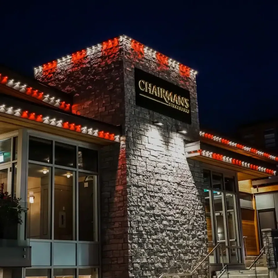 Red and white lights along a stone restaurant roofline