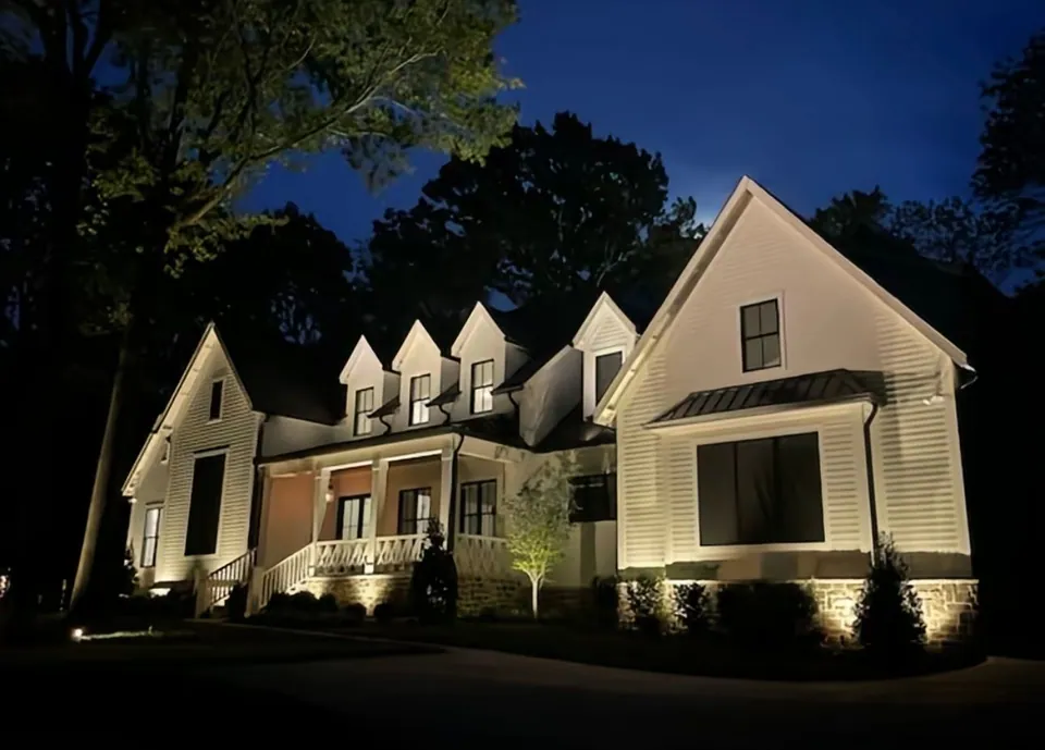 Warm uplighting across a white house with multiple dormers