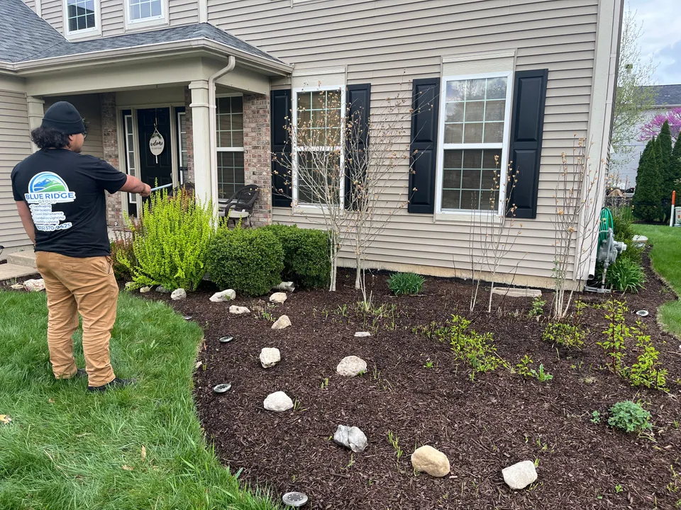 Crew member working beside the planting bed at a tan house